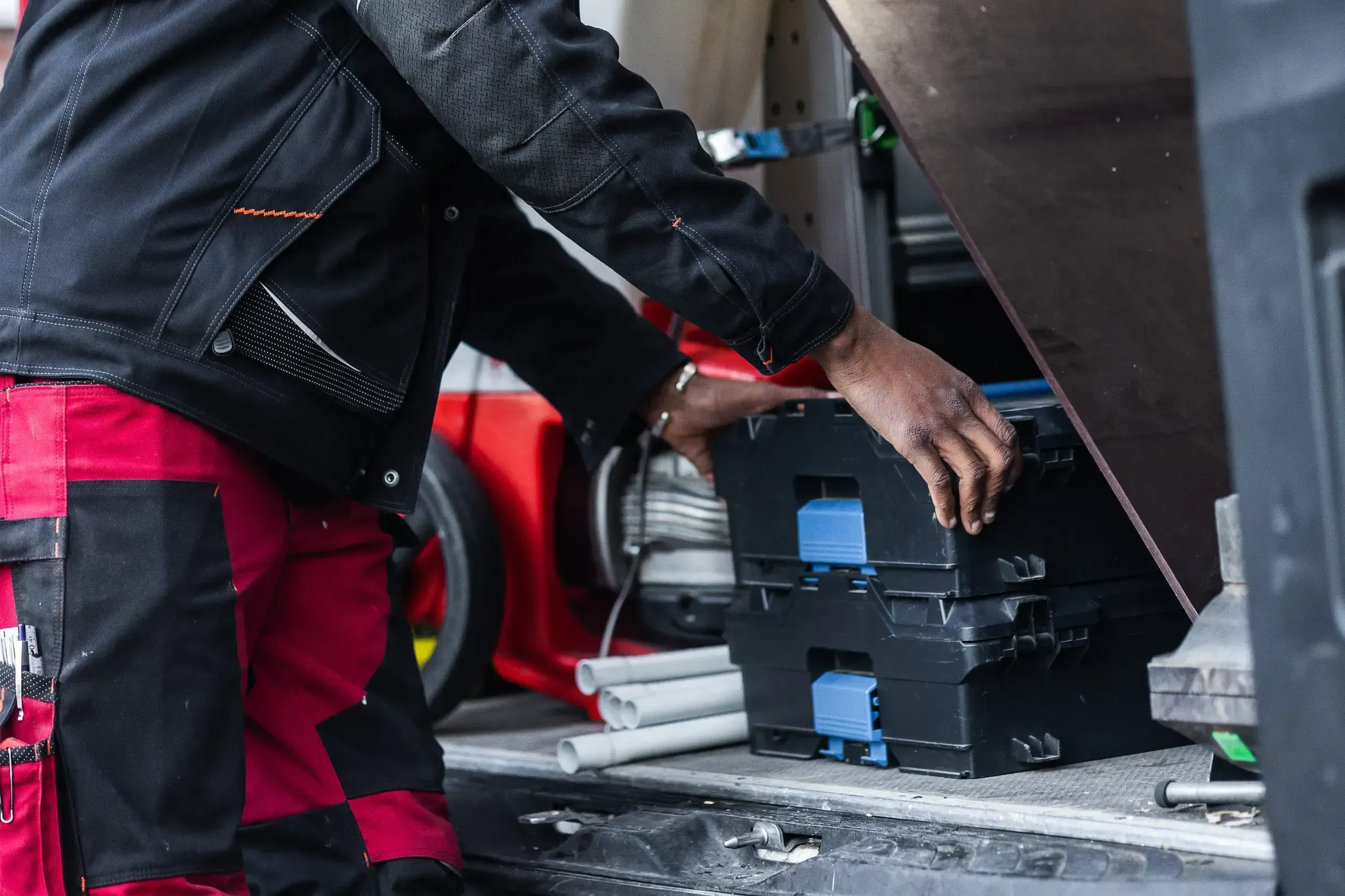 Heizungsmonteur entnimmt Werkzeugkoffer aus dem Servicefahrzeug für Installation und Wartung