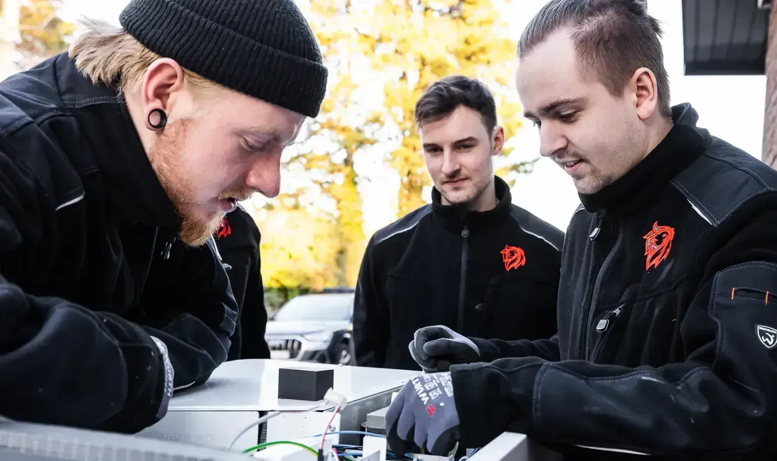 Drei Heizungsmonteure der Roten Löwen bei der Installation eines Heizsystems im Freien
